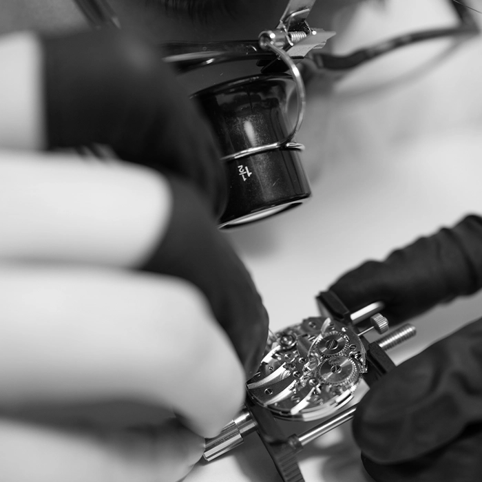 Un orologiaio con la lente al lavoro su un movimento OISA